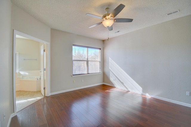 spare room with wood finished floors, visible vents, and a textured ceiling