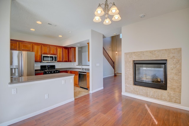 kitchen with visible vents, light wood finished floors, a peninsula, stainless steel appliances, and a glass covered fireplace