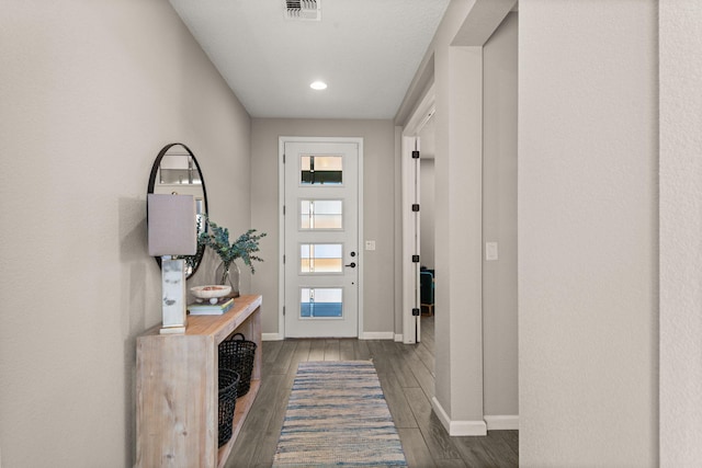 foyer with visible vents, baseboards, and dark wood-style flooring