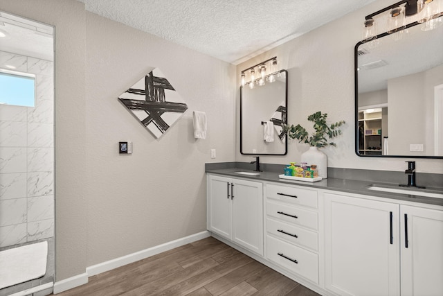 bathroom featuring a textured ceiling, wood finished floors, and a sink