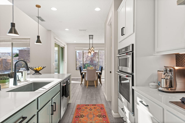 kitchen with a sink, tasteful backsplash, white cabinetry, appliances with stainless steel finishes, and light countertops