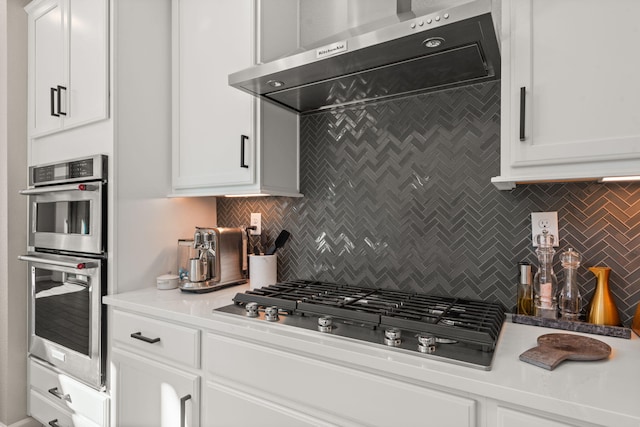 kitchen featuring tasteful backsplash, appliances with stainless steel finishes, exhaust hood, and white cabinetry