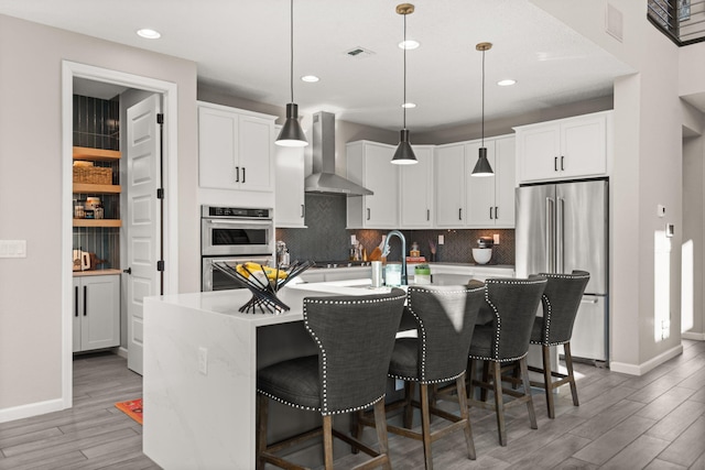 kitchen featuring stainless steel appliances, tasteful backsplash, visible vents, and wall chimney exhaust hood