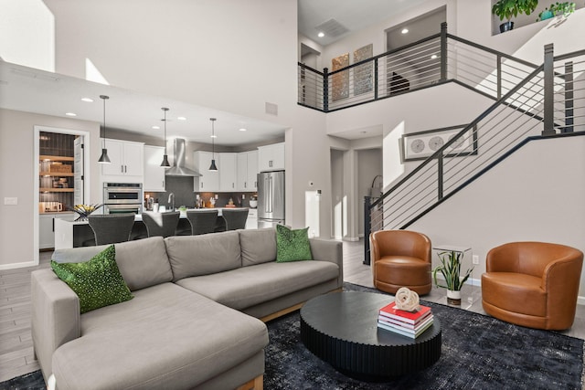 living area with stairway, wood finished floors, visible vents, baseboards, and recessed lighting