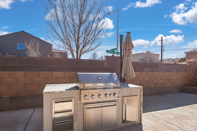 view of patio with area for grilling, exterior kitchen, and fence