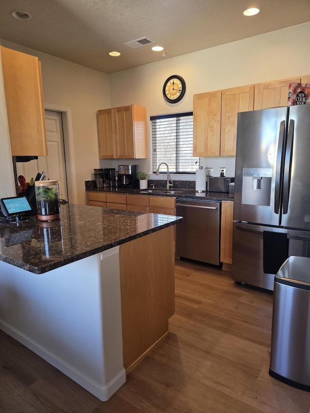 kitchen featuring a sink, a peninsula, light brown cabinets, and stainless steel appliances