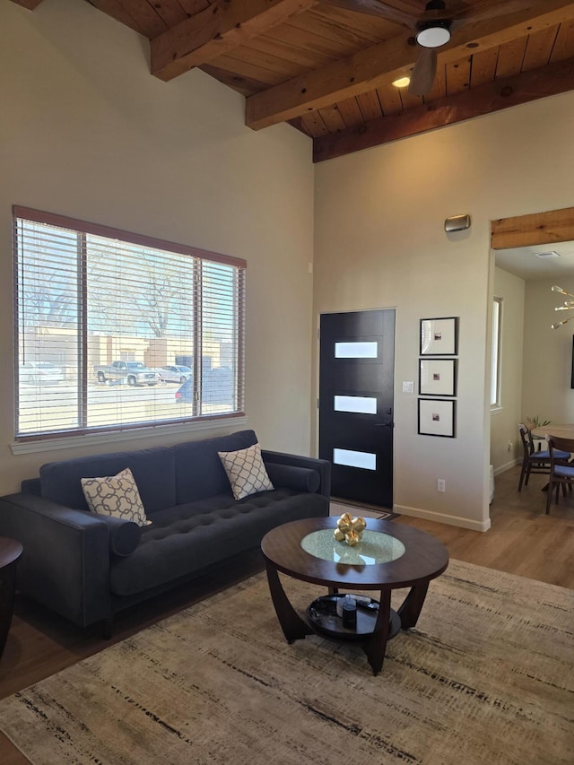 living area with wooden ceiling, light wood-style flooring, baseboards, and beam ceiling