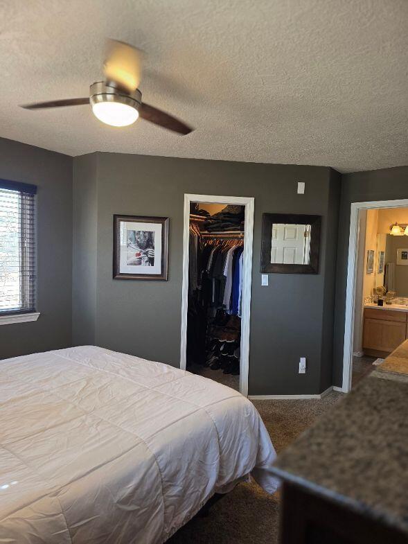 bedroom with carpet floors, ceiling fan, a closet, a textured ceiling, and a walk in closet