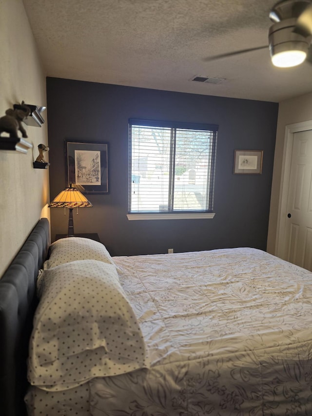 bedroom featuring visible vents, a textured ceiling, and ceiling fan