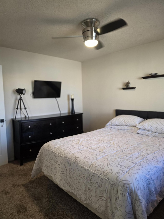 bedroom featuring dark carpet, a textured ceiling, and a ceiling fan