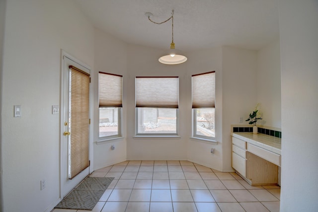 interior space with light tile patterned floors and built in desk