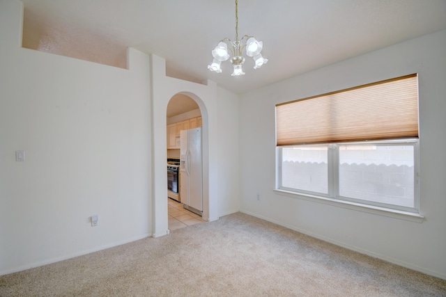 spare room with light carpet, arched walkways, lofted ceiling, and a chandelier