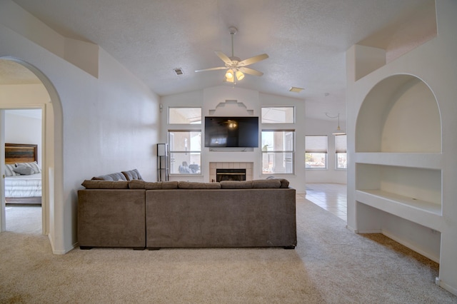 living room featuring carpet flooring, a fireplace, a textured ceiling, and lofted ceiling