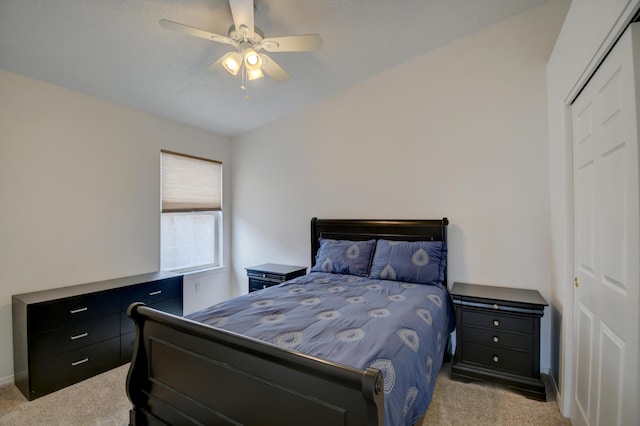 bedroom featuring a closet, light colored carpet, and a ceiling fan