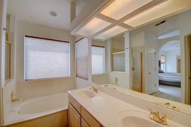 ensuite bathroom featuring a sink, visible vents, a garden tub, and a shower stall