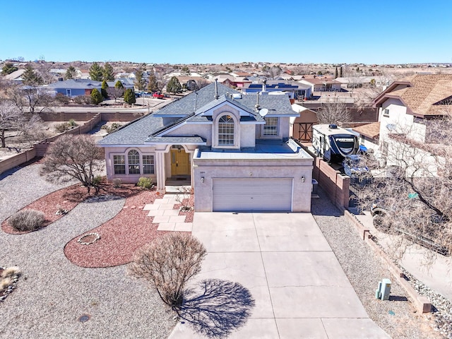 traditional-style house with stucco siding, driveway, fence, a residential view, and a garage