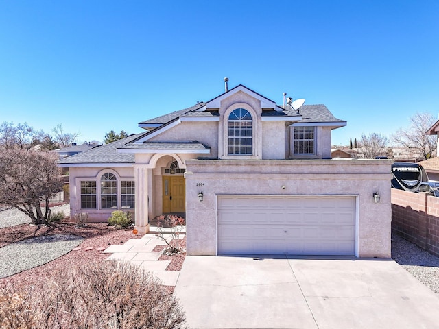 view of front of property featuring stucco siding, a garage, driveway, and fence