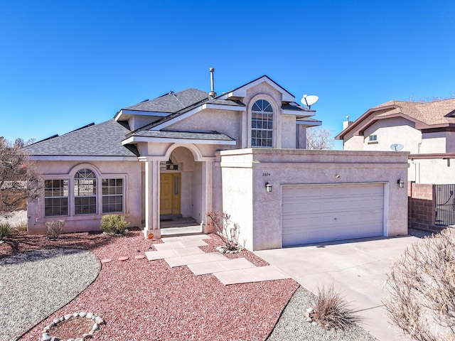 view of front of house featuring roof with shingles, driveway, and stucco siding