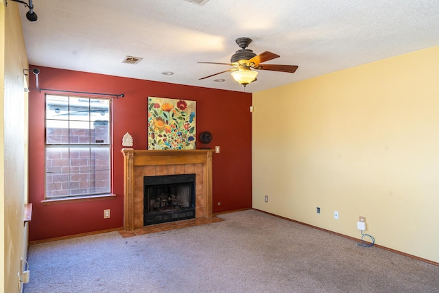 unfurnished living room featuring carpet, baseboards, visible vents, a tile fireplace, and a textured ceiling