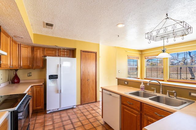 kitchen with white appliances, light countertops, brown cabinets, and a sink