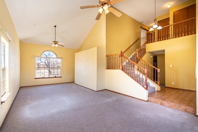 unfurnished living room with high vaulted ceiling, a ceiling fan, carpet floors, baseboards, and stairs