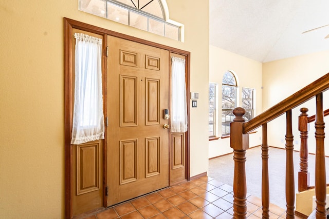 entrance foyer with tile patterned floors, stairway, baseboards, and high vaulted ceiling