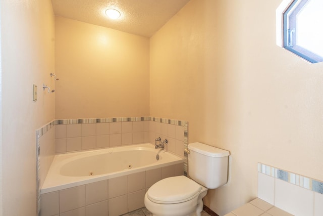 full bathroom featuring tile patterned flooring, toilet, a tub with jets, and a textured ceiling