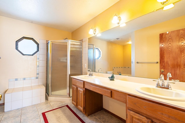 bathroom featuring double vanity, a stall shower, tile patterned floors, and a sink