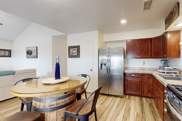 kitchen featuring light wood-type flooring, visible vents, a sink, appliances with stainless steel finishes, and light countertops