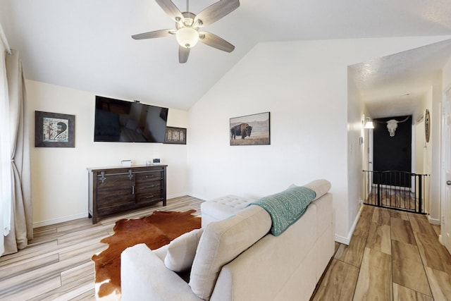 living area with light wood-type flooring, lofted ceiling, baseboards, and a ceiling fan