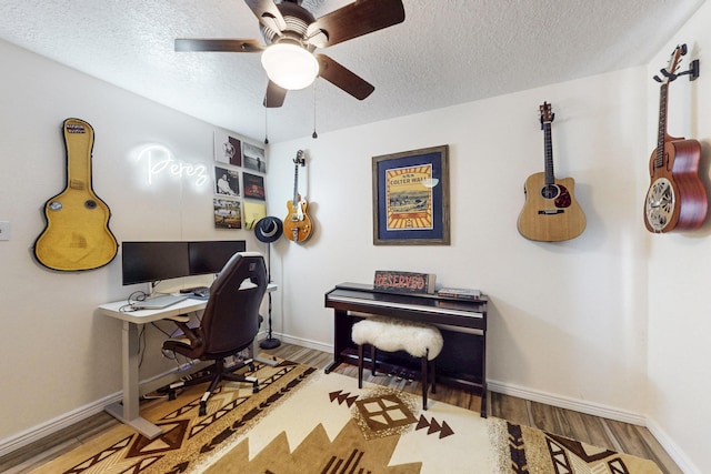 office area with a textured ceiling, a ceiling fan, baseboards, and wood finished floors