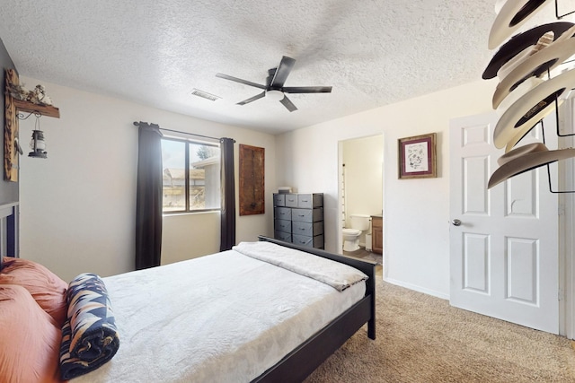 bedroom featuring visible vents, ceiling fan, carpet floors, ensuite bathroom, and a textured ceiling