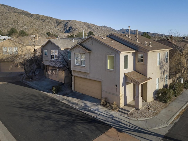 view of front facade featuring an attached garage, a mountain view, driveway, and stucco siding