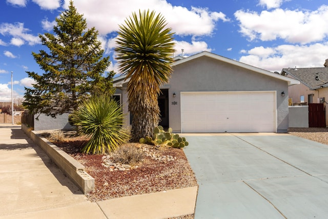 view of front of home featuring fence, a garage, driveway, and stucco siding