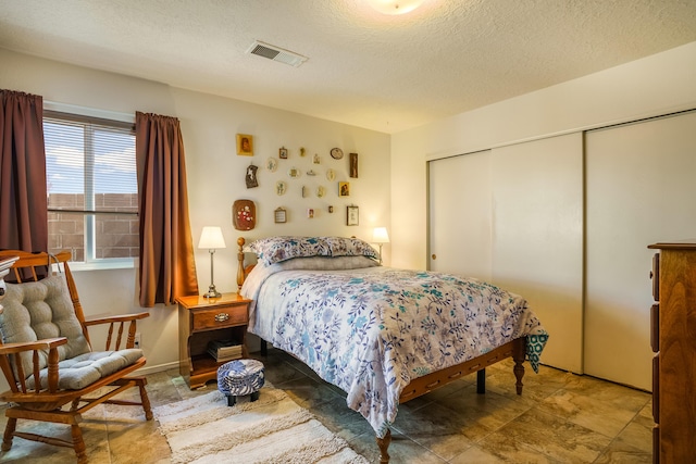 bedroom with visible vents, baseboards, a textured ceiling, and a closet