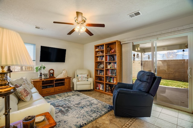 living area with visible vents, a textured ceiling, and a ceiling fan