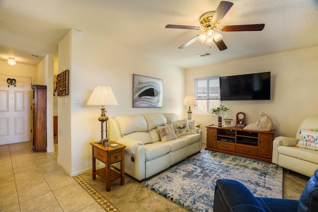 living area featuring visible vents, a textured ceiling, light tile patterned flooring, baseboards, and ceiling fan