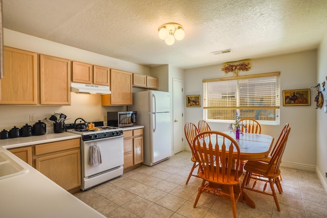 kitchen with visible vents, under cabinet range hood, light countertops, white appliances, and a sink