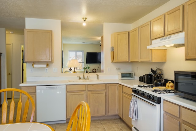 kitchen featuring light brown cabinetry, under cabinet range hood, light countertops, white appliances, and a sink