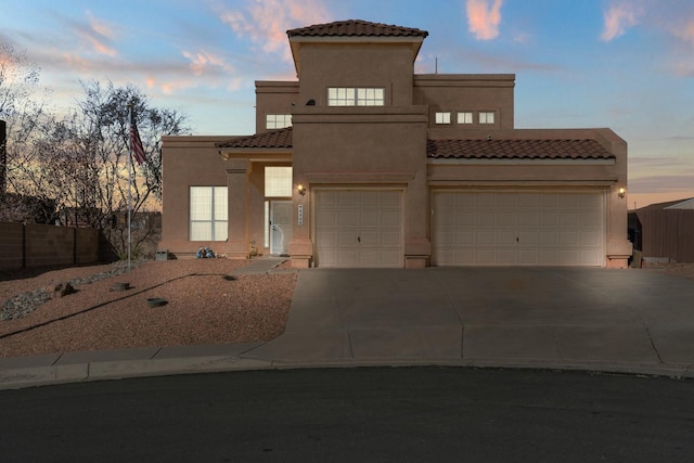 mediterranean / spanish-style house with a tile roof, fence, driveway, and stucco siding