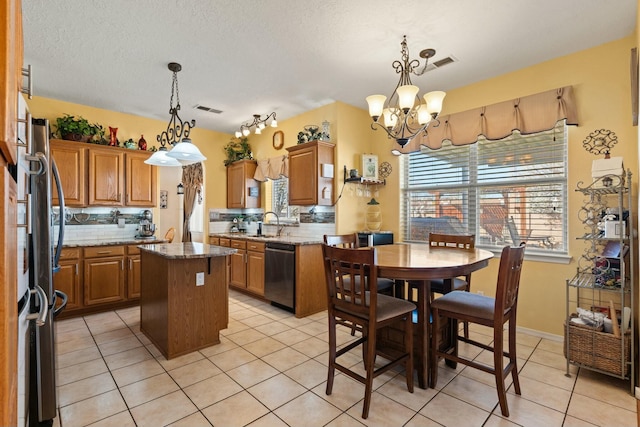 kitchen with dishwashing machine, visible vents, a kitchen island, light tile patterned flooring, and a notable chandelier