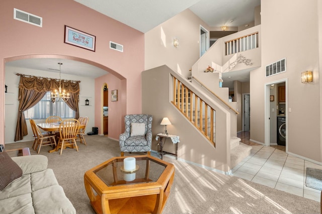 carpeted living area with arched walkways, visible vents, and washer / clothes dryer