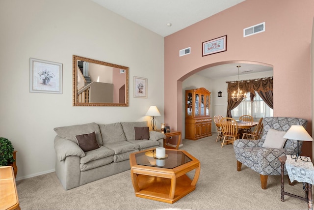 carpeted living area with a chandelier, visible vents, arched walkways, and baseboards