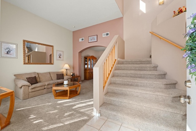 stairs featuring arched walkways, visible vents, tile patterned flooring, and carpet flooring