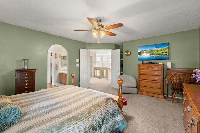 bedroom featuring ceiling fan, arched walkways, carpet floors, and a textured ceiling