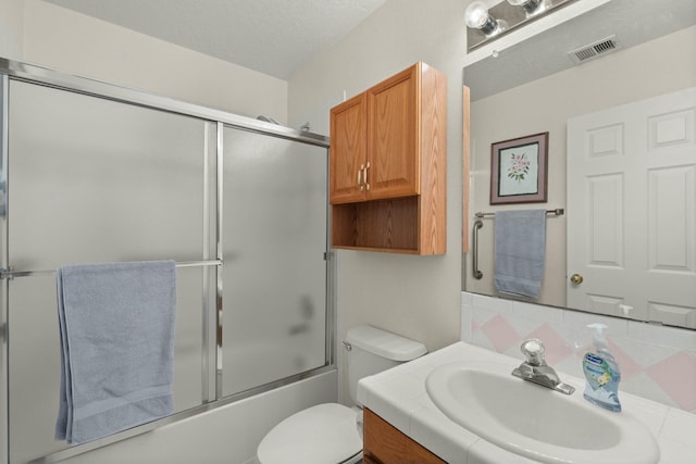 full bathroom featuring vanity, visible vents, a textured ceiling, toilet, and combined bath / shower with glass door