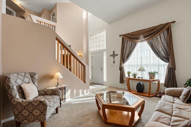 carpeted living room featuring plenty of natural light, stairway, and a towering ceiling