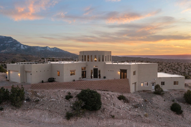 view of front of house with a mountain view, a garage, and stucco siding