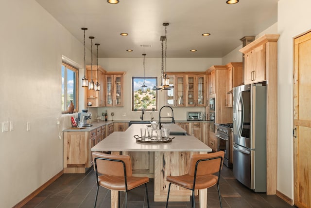kitchen featuring light countertops, an island with sink, light brown cabinetry, and stainless steel appliances