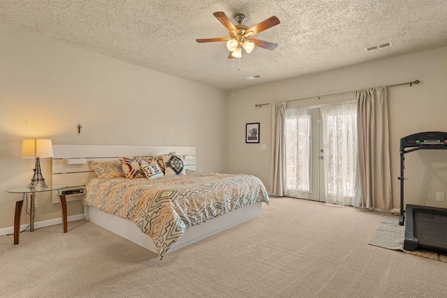 carpeted bedroom featuring access to exterior, visible vents, a textured ceiling, and a ceiling fan